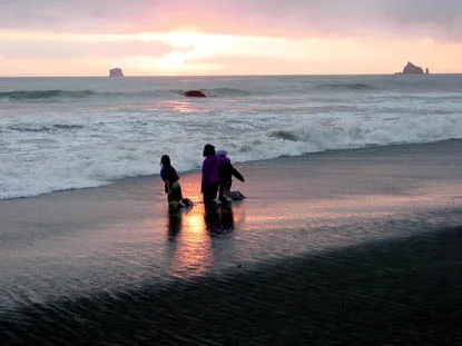 Sunset on Rialto Beach with visitors along the shore